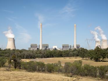 Farmland in foreground with polluting heavy industry in the background.